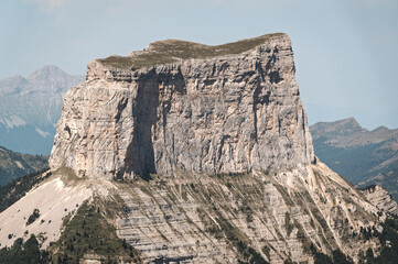 Gros plan vertical sur le Mont Aiguille. Détails de la roche et pinède dense.