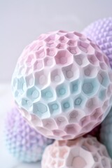 A honeycomb decorative ball sits alone on a white surface. The ball features a unique texture with soft pastel colors. Light reflects off the surfaces creating gentle highlights