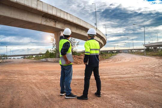 Construction Workers Overseeing Highway Project Under Cloudy Sky with Infrastructure Development and Progress