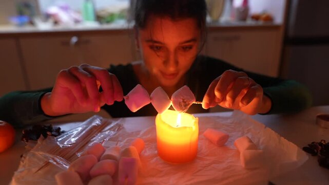 An Energetic Woman In Warm Kitchen Environment Checks Marshmallow Roasting Technique With Playful Enthusiasm