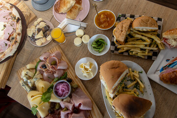 Top view of a table with a steak, cold cuts board, potatoes, hamburger and sweet treats, cornstarch alfajor