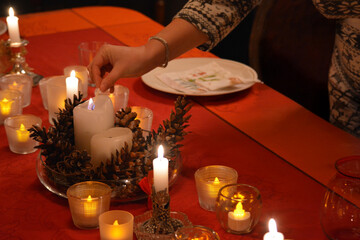 Festive table decoration for a Christmas dinner with someone lighting one of the candles