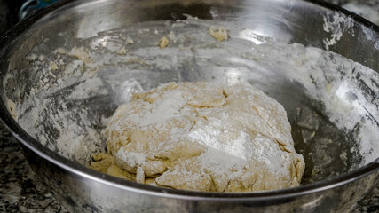 Dough is mixed in a bowl on a countertop in a kitchen while preparing for baking