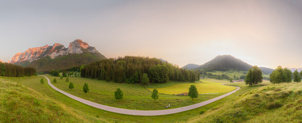 Fototapeta premium Meadow with road and bench during sunset in Berchtesgaden National Park