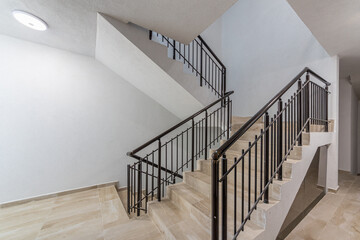Modern stair case between floors. Stairs with metallic rail in modern building. Interior of a contemporary apartment or office building. Architecture and real estate background.