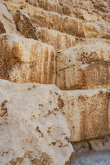 Large ancient limestone blocks form the base of a historical structure in the desert, showcasing...