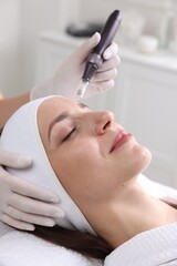 Fototapeta premium Woman undergoing microneedling procedure in beauty salon, closeup