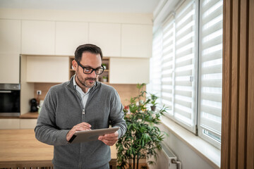 Man controlling smart home system using tablet in kitchen
