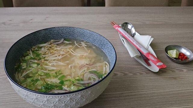 Fresh, hot pho bo soup served during a visit to a Vietnamese family, steaming with aromatic broth. Authentic home-cooked meal captures warmth, tradition, and cultural hospitality.