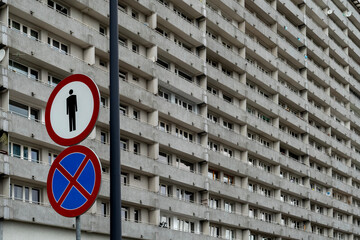 Large concrete apartment block with repetitive balconies and traffic signs in foreground