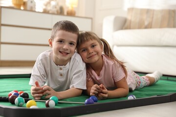 Cute kids on golf pool table at home