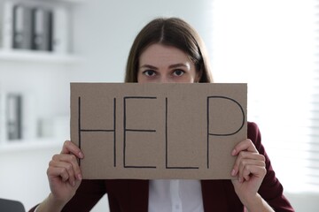 Woman holding sign with word Help in office