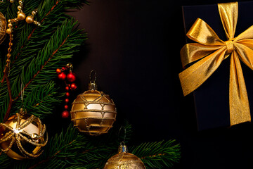 Christmas minimalistic and simple composition in mat black and gold color. Christmas decor, gold decorations on black background. Flat lay, top view with copy space. Autumn winter background.