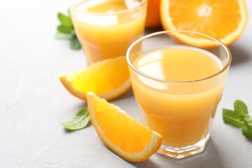 Fresh orange juice, mint and fruits on light table, closeup