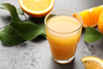 Fresh orange juice, fruits and leaves on grey table, closeup
