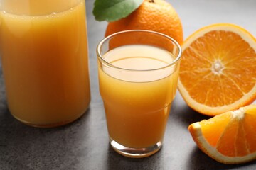 Fresh orange juice and fruits on grey table, closeup