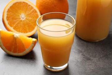 Fresh orange juice and fruits on grey table, closeup