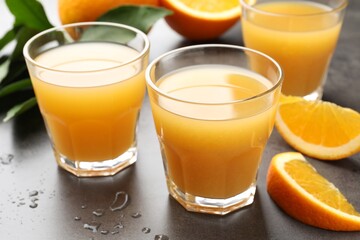 Fresh orange juice and fruits on grey table, closeup