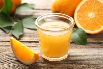 Fresh orange juice and fruits on wooden table, closeup