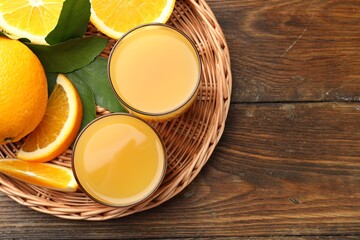 Fresh orange juice, fruits and green leaves on wooden table, top view. Space for text