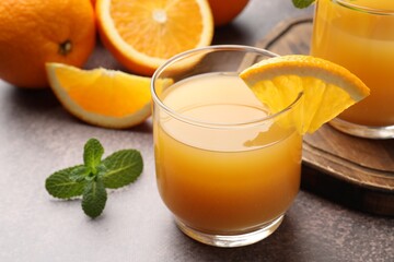 Fresh orange juice, mint and fruits on grey table, closeup
