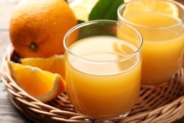 Fresh orange juice, fruits and green leaves on table, closeup