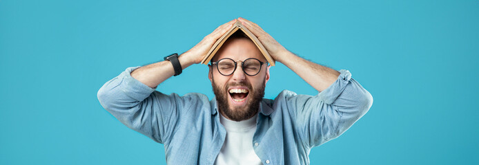 A man with glasses and a beard shows frustration while balancing a book on his head. His expression...