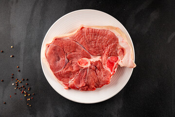 Bone-in ham steak, raw pork ham on the bone tasty snack fresh gourmet food background on the table  rustic food top view copy space