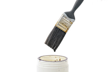 A black paint brush drips thick lacquer onto an open white can, isolated on a white background. Close-up view of painting tools