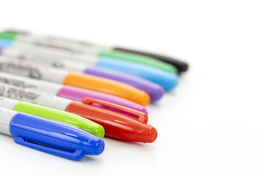 Close-up view of a set of colorful markers with caps on a clean white background showing various vibrant colors in a diagonal