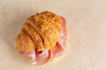 Savory Croissant with mortadella sausage, salume on a beige table surface.