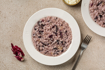 Plates with Italian risotto with round radicchio rosso and cheese. Beige table. Copy space.