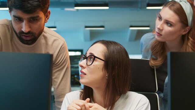 Team facing technical issue on monitor. Female professional showing disappointed reaction while checking failed task. Male coworker reviewing screen while woman observing. In busy office setting.