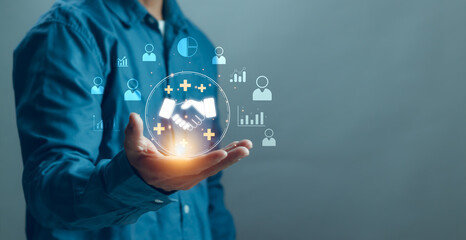 Businessman holding digital handshake icon on hands with virtual graphics, representing partner analysis, customer relationship concept, business trust, cooperation for corporate growth