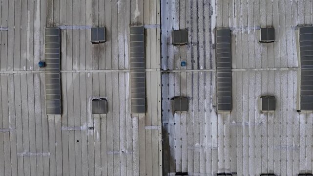 Drone shot of industrial hall rooftop with parallel panels, ventilation ducts and snow traces forming distinct geometric patterns