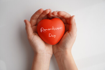 Remembrance Day. Hands holding a red heart with the words written on it. White background.