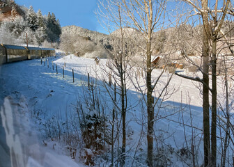 View from the window of a Himmelsstiege train on the railway line from Sankt P&ouml;lten to Mariazell into a snowy winter landscape with a blue sky, Austria