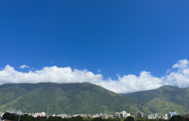  Lush green mountains overlooking a tropical cityscape - The skyline of Caracas, Venezuela, and El &Aacute;vila National Park on a sunny day