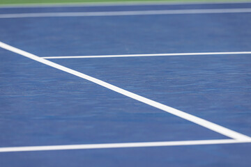 A tennis court that has been played on. The court is a hard court and blue.
