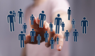 Concept of digital networking and people interaction. Hand touches virtual human icons. Represents teamwork, co