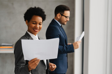 African American businesswoman and businessman reviewing documents in an office.