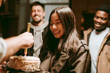 Friends celebrate a birthday with laughter and cake in a cozy indoor setting during a joyful evening gathering