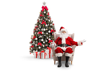 Santa claus sitting in armchair in front of a decorated christmas tree