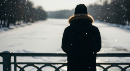 Person in winter coat looking at snowy frozen river.