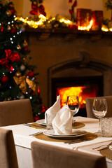 Cozy Christmas dining room with a decorated tree, warm fireplace, festive lights, and an elegant table setting ready for a holiday celebration.