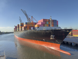Naklejka premium container cargo freight ship moored in port. cranes lift and move containers for loading and unloading. Modern logistics, container transport, maritime shipping, global trade and freight handling.