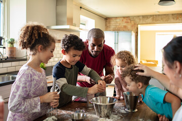 Adult father and young children baking together in home kitchen, joyful