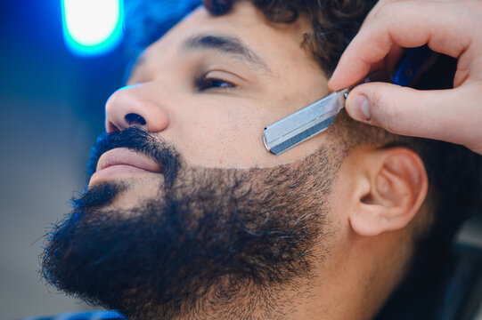 Man getting beard lined up with straight razor