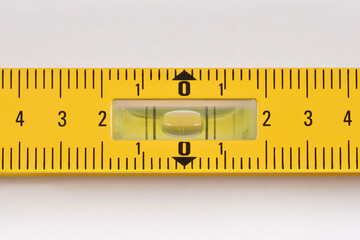 A close-up shot of a yellow tool with a clear plastic vial filled with liquid and an air bubble, used for measuring level