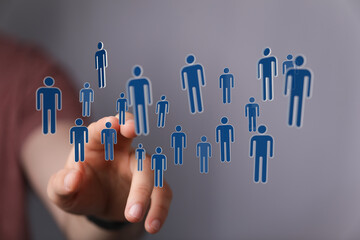 Visualize connection with this image of a hand touching digital human icons representing a network of people. Ideal for social media and technol